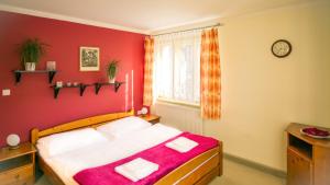 a bedroom with a bed with red walls and a window at penzion Horácko in Unčín