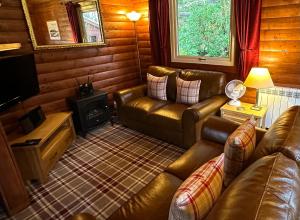 ein Wohnzimmer mit Ledermöbeln und einem Herd in der Unterkunft Pucks Glen Lodges, Rashfield, by Dunoon in Dunoon