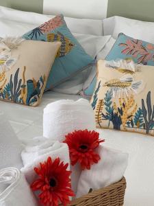 Una cama con toallas y una cesta con flores. en Casa - Torre dell'Orologio en Canosa di Puglia