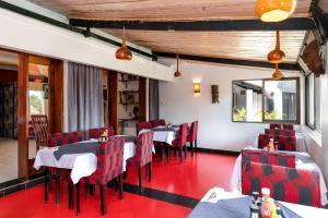 a dining room with tables and red chairs at 2 Friends Beach Hotel in Entebbe