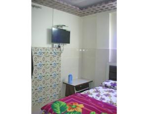 - une chambre avec un lit et une télévision murale dans l'établissement Hotel Kanha Dham, Kanpur, à Kanpur