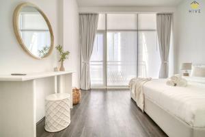 ein weißes Schlafzimmer mit einem großen Bett und einem Spiegel in der Unterkunft Beautiful 2 Bedroom Apartment in J8 in Dubai