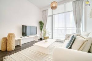 a white living room with a white couch and a tv at Beautiful 2 Bedroom Apartment in J8 in Dubai