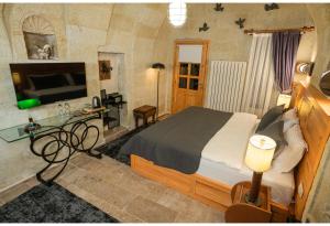 a bedroom with a bed and a desk and a television at Bala Cave House in Avanos