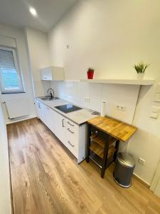 a kitchen with white cabinets and a wooden table at Apartment am Zollverein -WiFi - Parking for free in Essen
