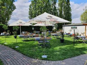 eine Gruppe von Tischen und Sonnenschirmen im Gras in der Unterkunft Landhaus Spickermann in Xanten