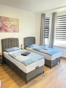 two beds in a room with two windows at Apartment am Zollverein -WiFi - Parking for free in Essen