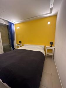 sypialnia z czarnym łóżkiem i żółtą ścianą w obiekcie Malusi B&B w mieście Palermo