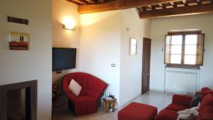 a living room with a red couch and a tv at Podere Le Volpaie, Volterra, Tuscany in Montecatini Val di Cecina