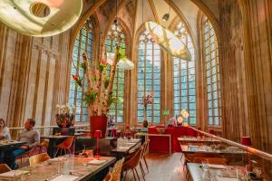 a restaurant with people sitting at tables in a building at Kruisherenhotel Maastricht - Oostwegel Collection, member of Design Hotels in Maastricht