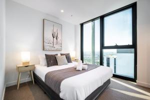 - une chambre avec un grand lit et une grande fenêtre dans l'établissement Mega Style Apartments Victoria One, à Melbourne