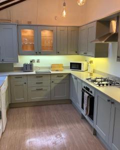uma cozinha com armários brancos e electrodomésticos brancos em River Cottage em Conwy