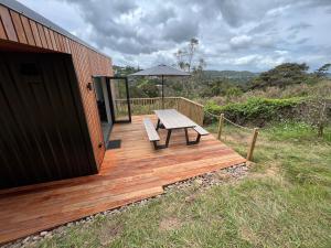 a wooden deck with a bench and an umbrella at Hidden Valley Waiheke in Palm Beach