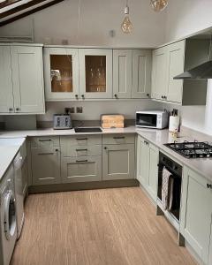 a kitchen with white cabinets and white appliances at River Cottage in Conwy