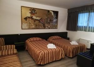 a hotel room with two beds and a painting on the wall at Green Hotel in Poviglio