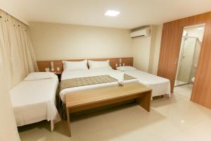a hotel room with two beds and a walk in shower at Sun Residence in Fortaleza