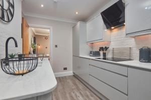 a kitchen with white cabinets and a counter top at The Swan Apartment - Free parking in Harrogate