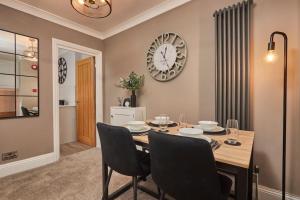 a dining room with a table and chairs and a clock at The Swan Apartment - Free parking in Harrogate