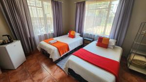two beds in a room with two windows at Casa Feliz in Mokopane