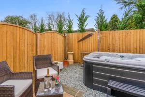un patio trasero con bañera de hidromasaje y valla en The Thatch House, en Woolstone