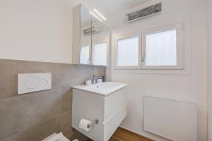 bagno bianco con lavandino e specchio di Casa Elvezia - Happy Rentals a Piandera