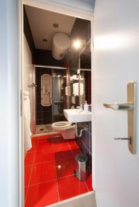 łazienka z toaletą, umywalką i czerwoną podłogą w obiekcie Centar W w mieście Osijek