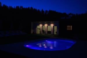 Nachtansicht eines Hauses mit blauem Pool in der Unterkunft Moon House in Cluj-Napoca
