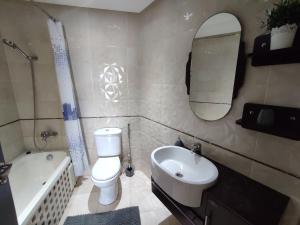 a bathroom with a toilet and a sink and a mirror at Chaleureux Appartement à 1 min à pied de la Mosquée Hassan II in Casablanca