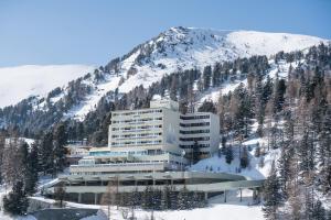 un edificio al lado de una montaña nevada en Panorama Hotel Turracher Höhe, en Turracher Höhe
