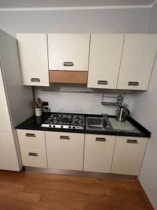 uma cozinha com armários brancos, um fogão e um lavatório em Suite Luxury [Duomo - SanSiro] em Milão