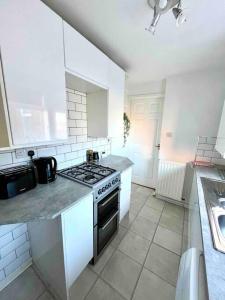 een witte keuken met een fornuis en een wastafel bij Close to city centre-Quayside bright apartment in Gateshead