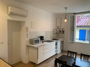 cocina con armarios blancos, mesa y microondas en Marseille LOFT 50m2 au cœur du Cours Julien en Marsella