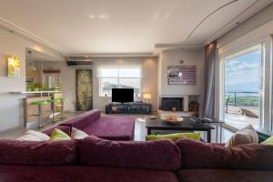 a living room with a purple couch and a tv at Harmony Maisonette in Schinias