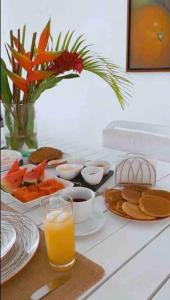a table with breakfast foods and a glass of orange juice at Lomas del Encanto, villa en la montaña cerca del mar in La Asunción
