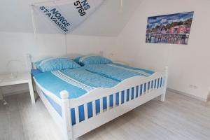 - un lit blanc avec une couette bleue dans la chambre dans l'établissement Die Strandbutze - a74112, à Eckernförde