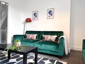 un divano verde in un soggiorno con tavolo di 5 BDRM house less than 10 mins to Newcastle a Gateshead
