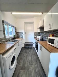 una cucina con armadi bianchi, lavatrice e lavandino di 5 BDRM house less than 10 mins to Newcastle a Gateshead