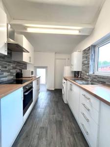 una cucina con armadietti bianchi e pavimenti in legno di 5 BDRM house less than 10 mins to Newcastle a Gateshead