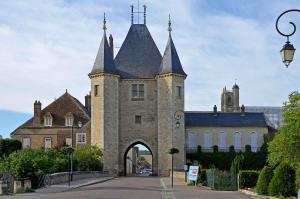 un antiguo edificio con un arco delante de él en L'Expédition BEST KEYS - Centre Ville - Netflix en Villeneuve-sur-Yonne