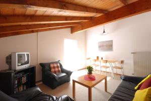 uma sala de estar com um sofá, uma televisão e uma mesa em Casa Esmeralda em San Nazzaro