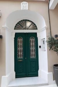 a green door on a white building with stairs at Platanos house in Plomarion