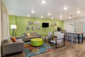 WoodSpring Suites Jacksonville - South في جاكسونفيل: غرفة معيشة مع أريكة وكراسي وطاولة