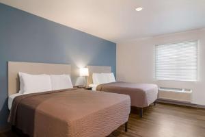 WoodSpring Suites Jacksonville - South في جاكسونفيل: غرفة فندقية بسريرين ونافذة