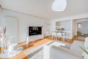 a white living room with a white couch and a tv at Honeymoon with Stunning View - Happy.Rentals in Castagnola