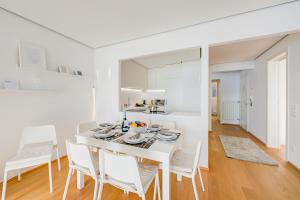 ein weißes Esszimmer mit einem weißen Tisch und Stühlen in der Unterkunft Honeymoon with Stunning View - Happy.Rentals in Castagnola