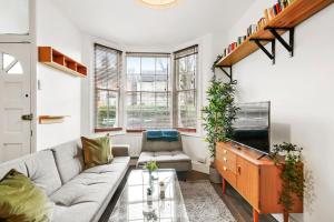 a living room with a couch and a tv at 2 Bed Garden Flat Leyton Village in London