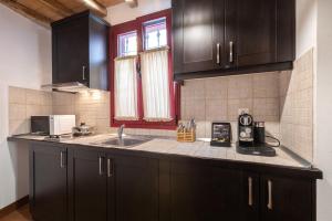 a kitchen with black cabinets and a sink at The Varos Residences Hotel in Város