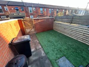 un patio trasero con césped verde frente a un edificio de ladrillo en Stylish newly renovated home near Manchester City Centre, en Radcliffe