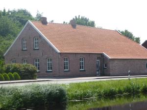 un bâtiment en briques avec un toit en tuiles orange dans l'établissement Ferienwohnung Elise im Gulfhof am Kanal, à Großefehn 
