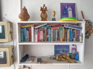 a white book shelf with books on it at Summer Lanka Surf House in Hikkaduwa